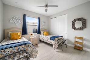 The bedroom has two twin beds with matching linens and throw pillows on top. The walls are painted a calming color, creating a relaxing atmosphere. Twin beds can also be converted to a 1 king bed upon request and ample notice.