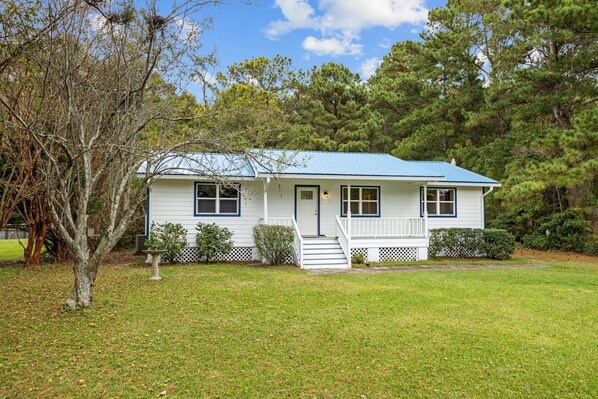 Charming bungalow with a spacious front porch and striking blue metal roof.