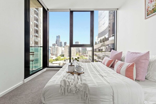 The bedroom with a queen sized bed and city views.