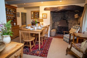Dining table and chairs laid for dinner. Inglenook fireplace