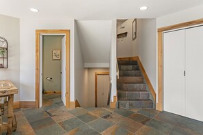 A tiled hallway features a closed closet door, an open bathroom door, and a staircase leading up and down.
