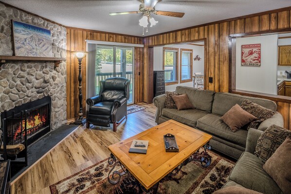 Living room with a stone fireplace and sliding doors for mountain air.