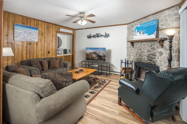 Warm living space with stone fireplace and TV.