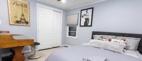 The bedroom includes a full-sized bed, desk workspace, & ceiling fan