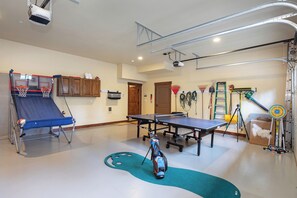 The room includes a basketball arcade game, a ping-pong table, and a small putting green