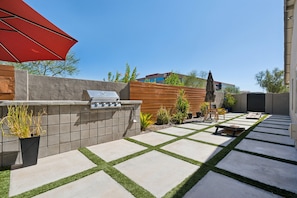 Sparkling heated optional pool, sun loungers, custom-built BBQ area, mobile cooler, cornhole, floating basketball hoop, outdoor dining table, patio furniture, and ample lounge areas.