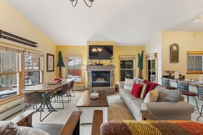 Open-concept living area featuring a mounted TV above a gas fireplace, queen sleeper sofa, and queen Murphy bed.
