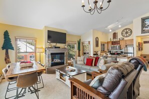 Open-concept living area featuring a mounted TV above a gas fireplace, queen sleeper sofa, and queen Murphy bed.
