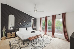 A peaceful retreat awaits from the comforts of this primary bedroom with vaulted ceilings, a Texas-inspired accent wall, and a plush king bed you can sink into!