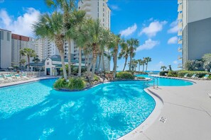 Oversized lagoon pool that is directly overlooking the beach with lush palms and waterfall islands
