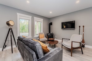 The living room offers a perfect blend of modern comfort and cottage charm, with plush seating and a rustic stove to keep you warm on cool evenings.