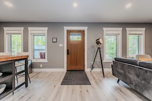 A bright and airy entrance greets you as you step inside the open-concept living space, featuring large windows that flood the room with natural light.