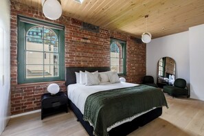 The ground-floor primary bedroom highlights arched windows with a plush king-sized bed and wardrobes for your belongings.
