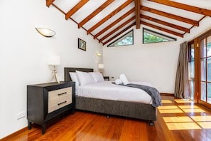 Spacious main bedroom featuring a queen bed adorned with professionally laundered linens for a luxurious touch, a walk-in closet, and direct access to a serene courtyard.