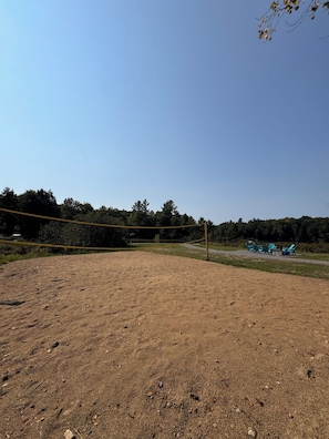 Sandy Volleyball pit. w/ net and ball. with view of the water