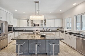 Bright gourmet kitchen with sleek finishes and a grand island.