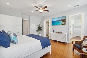 Master bedroom with warm wood floors and airy elegance with TV.