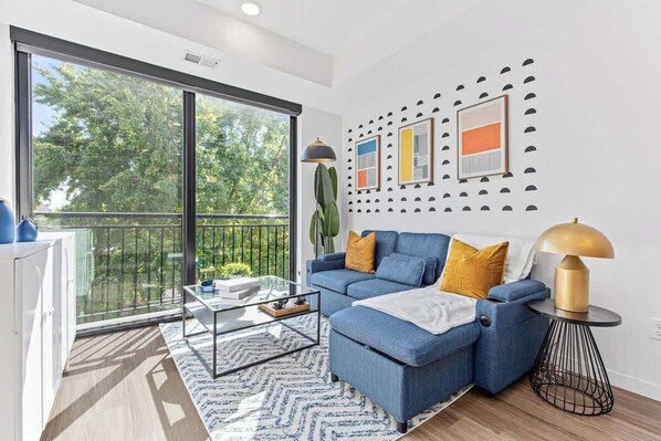 Right, modern apartment with cozy blue sofa, balcony views, & chic decor touches.