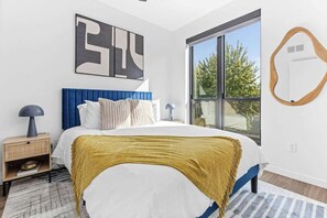 Serene bedroom with a plush velvet headboard, cozy linens, and natural light.