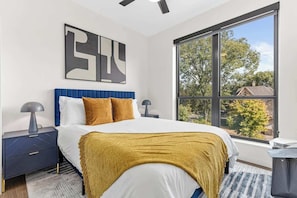 Cozy bedroom with a velvet headboard, warm accents, and stunning natural light.