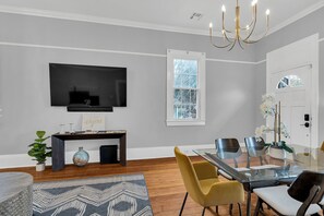 Charming dining space with exposed brick, chic chandelier, and a cozy fireplace setting the perfect ambiance for meals or gatherings.