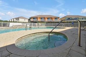 Enjoy the resort-style amenities with this large community pool and adjacent hot tub, surrounded by lush landscaping and lounge seating. Ideal for relaxing after a day at nearby attractions.