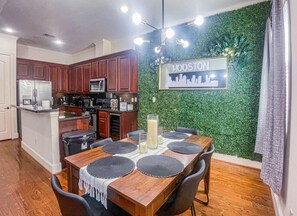 Chic dining area set against a vibrant green accent wall, perfect for enjoying meals, game nights, or remote work in style.