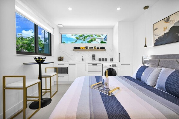 Modern studio with sleek kitchen, cozy bed, and ample natural light.