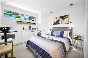 Bright and modern studio with a cozy bed, sleek kitchen, and elegant decor.