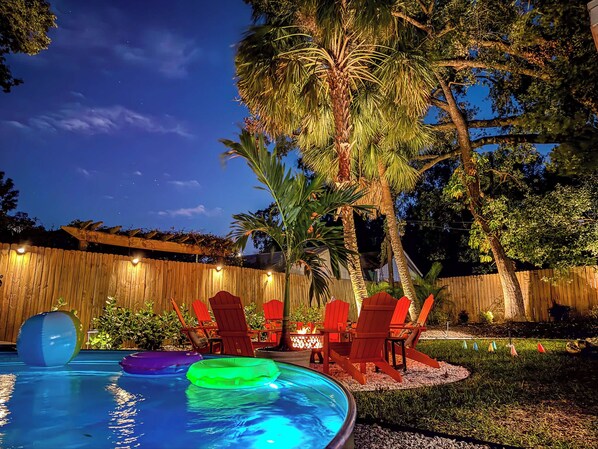 Oasis-style backyard with ambient lighting, fire pit, and pool to hang out with friends and family