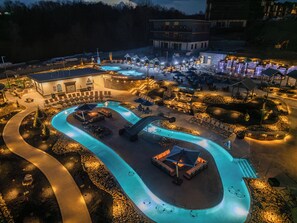 An aerial view of the resort’s lazy river at night, beautifully lit with glowing blue water and surrounded by cabanas and lounge chairs.