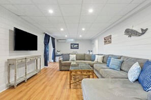 Basement w/ sectional, TV, seating area, ping pong table, full bath & bedroom. 