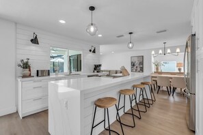 The kitchen of the home has a farm and beach house vibe and has a large center island with seating for 4 