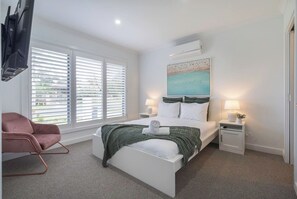 The light-filled primary bedroom located downstairs features a queen-size bed, a walk-in robe and a dual-access ensuite.