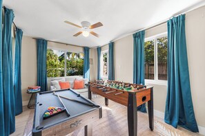 Game room with foosball, pool table, windows, and ceiling fan