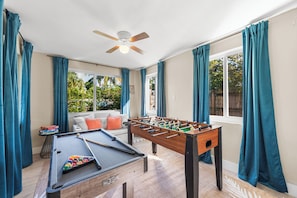 Game room with foosball, pool table, windows, and ceiling fan