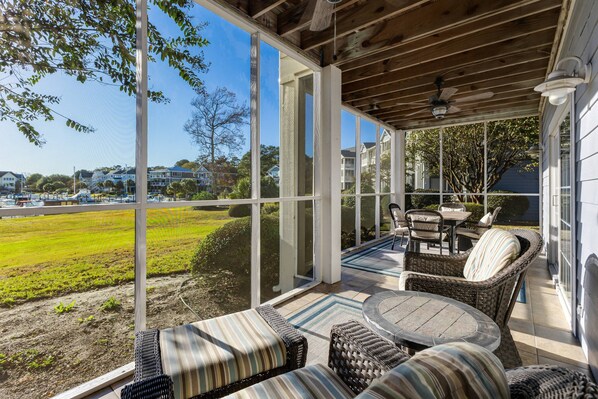 Enjoy serene views from this screened-in porch, featuring comfortable seating and a dining area, perfect for relaxing!