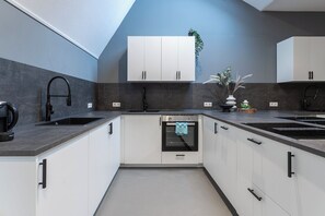 A sleek, modern kitchen showcasing white cabinetry and dark countertops, complemented by stainless steel appliances and subtle greenery for a touch of freshness.