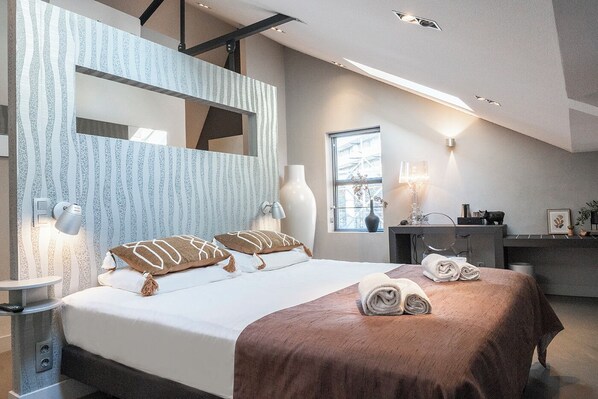 A beautifully designed bedroom featuring a large, comfortable bed with warm accents, stylish decor, and natural lighting for a cozy and inviting atmosphere.