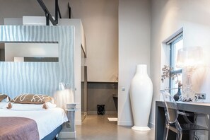 A modern, well-lit bedroom with a comfortable bed, sleek design elements, and a workspace, perfect for both relaxation and productivity.