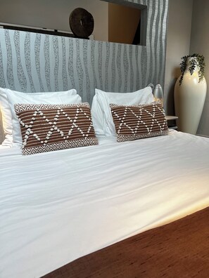 A comfortable bed with crisp white linens and patterned pillows, creating a cozy and stylish sleeping space.