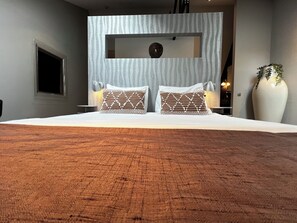 A cozy bed with warm-toned bedding, patterned pillows, and a modern partition for a stylish look.