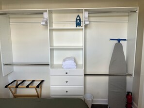 Open closet with iron/ironing board and luggage rack