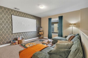 Move room with plush couch and large screen projector
