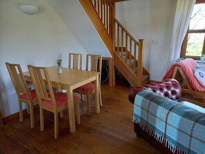 Dining table and chairs, back of the sofa and staircase going up stairs