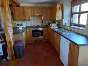 Kitchen with wall and floor cabinets, oven and hob, microwave