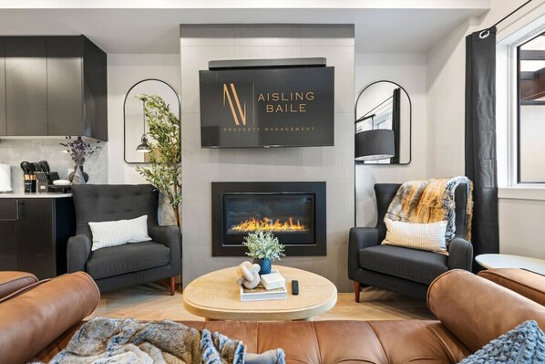 Living room with a gas-lit fireplace, luxurious seating options & a Smart TV.