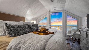 Drift off to sleep in this serene bedroom with stunning sunset views, complete with luxurious bedding and a cozy atmosphere