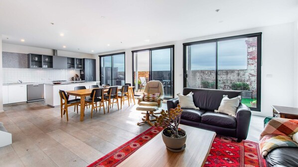Bright and spacious open-plan living area with modern kitchen, dining space, and cozy lounge, perfect for relaxing and entertaining.