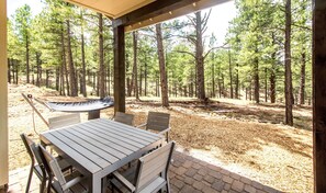 Relax in a private backyard overlooking a serene forest, perfect for wildlife spotting or unwinding in nature.